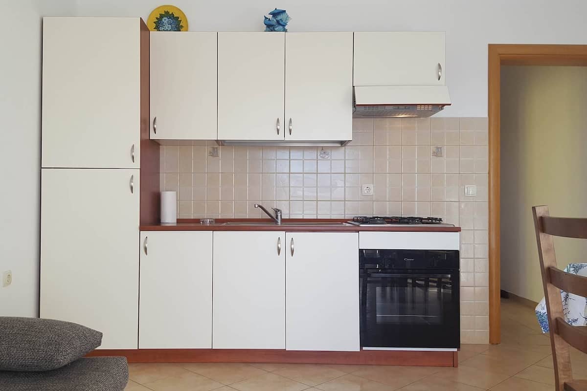 A compact kitchen with white cabinets, a built-in dishwasher, and a stove.