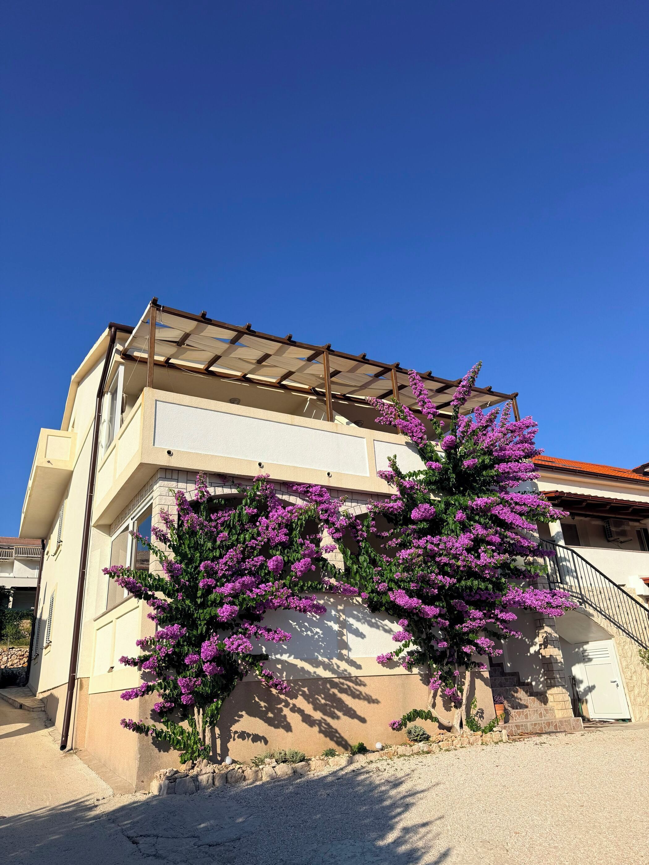 Um edif ício de dois andares com varanda e pérgola.