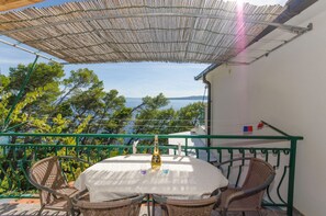 Ein Balkon mit Korbstühlen, einem Tisch und einer Weinflasche.