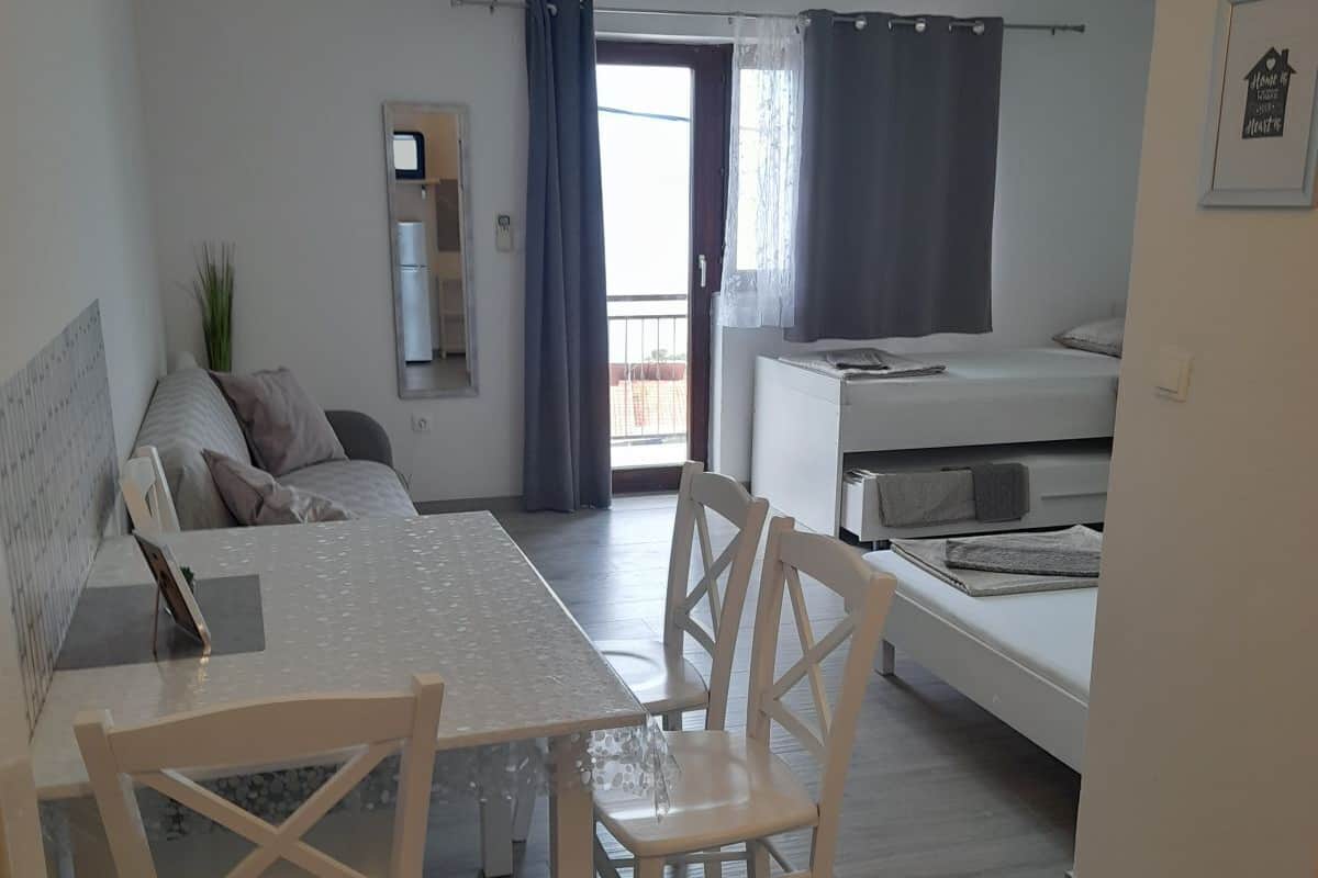 A modern, well-lit room with a dining table, chairs, a sofa, and a bed.