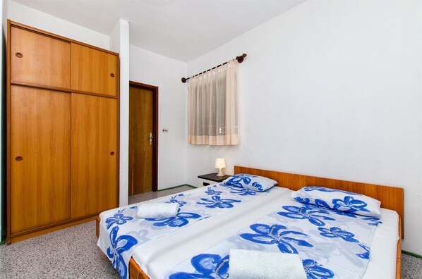 Een slaapkamer met een tweepersoonsbed, een houten garderobe en een nachtkastje met een lamp.