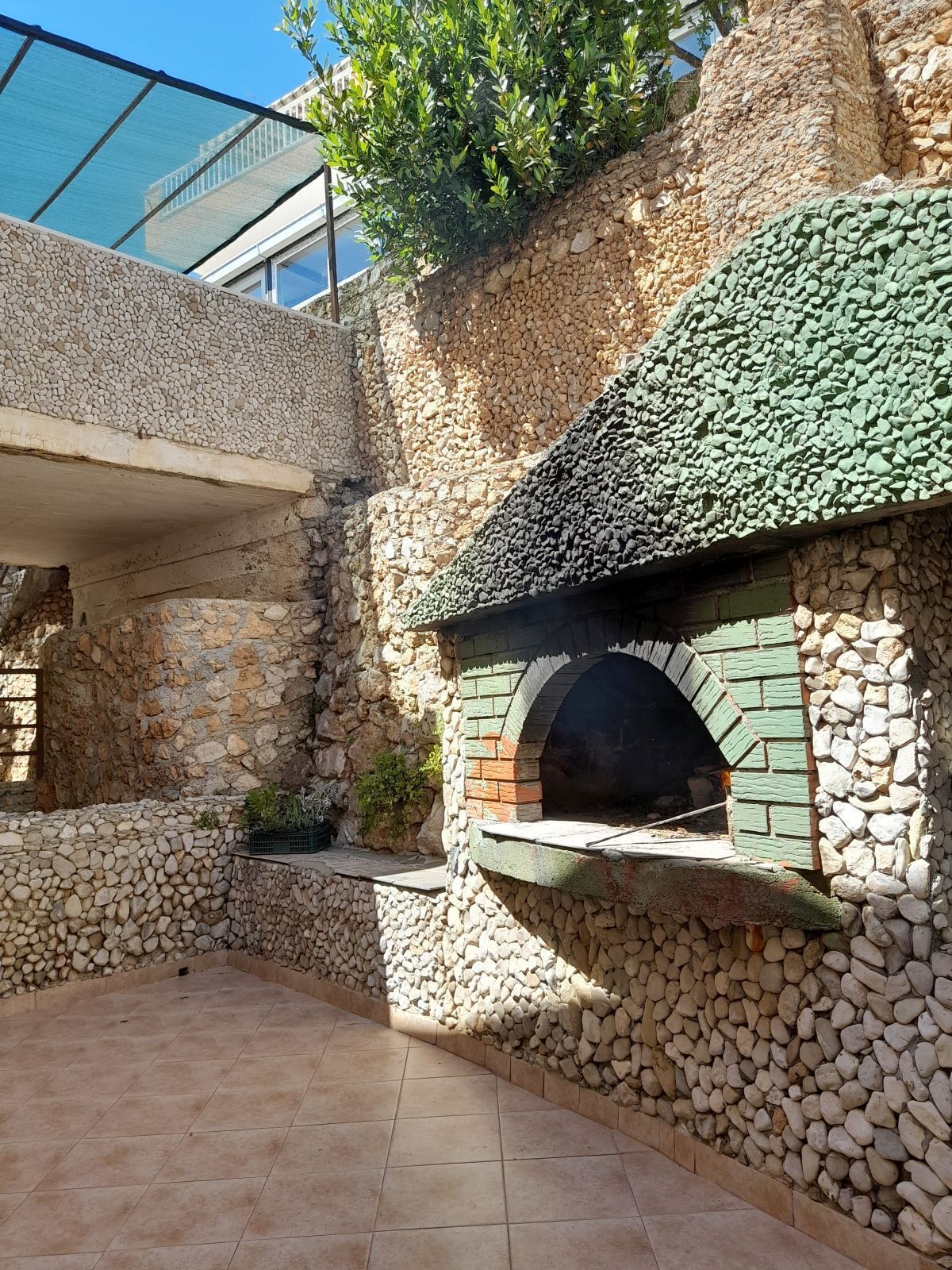Eine Terrassenfläche im Freien mit einer Steinmauer und einem Backofen aus Ziegeln.