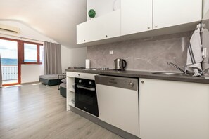 A modern kitchen with white cabinetry, a built-in oven, and a stainless steel sink. - Apartments Stipe (Omis)