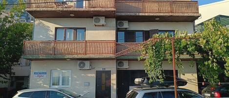 Un edificio residencial de varios pisos con balcones, unidades de aire acondicionado y un letrero que indica que es un complejo de apartamentos.