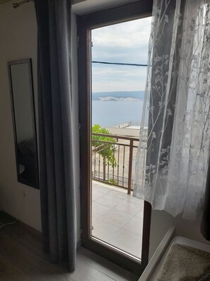 Une pièce dotée d’une grande porte-fenêtre coulissante donnant sur un balcon avec vue sur une étendue d’eau et sur la terre ferme au loin.