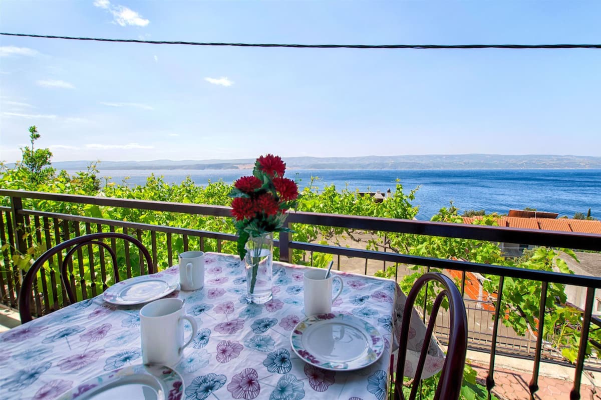 A table set for two with a view of the sea and hills.