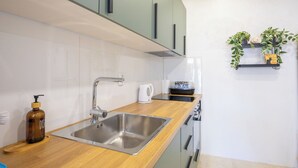 Eine moderne Küche mit Spüle aus Edelstahl, einer Holz Arbeitsplatte und grünen Schränken.