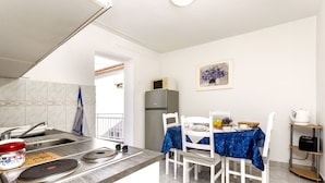 A compact kitchen with a sink, stove, and dining area with chairs and a table.
