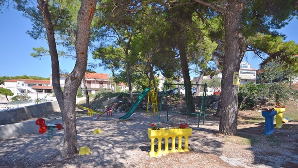 A playground with a slide, swings, and a climbing structure. - Apartments Goroslava (Tribunj)