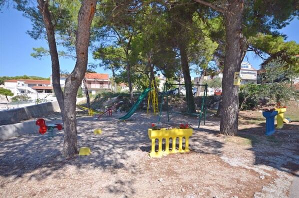Une aire de jeux avec un toboggan, des balançoires et une structure d’escalade.