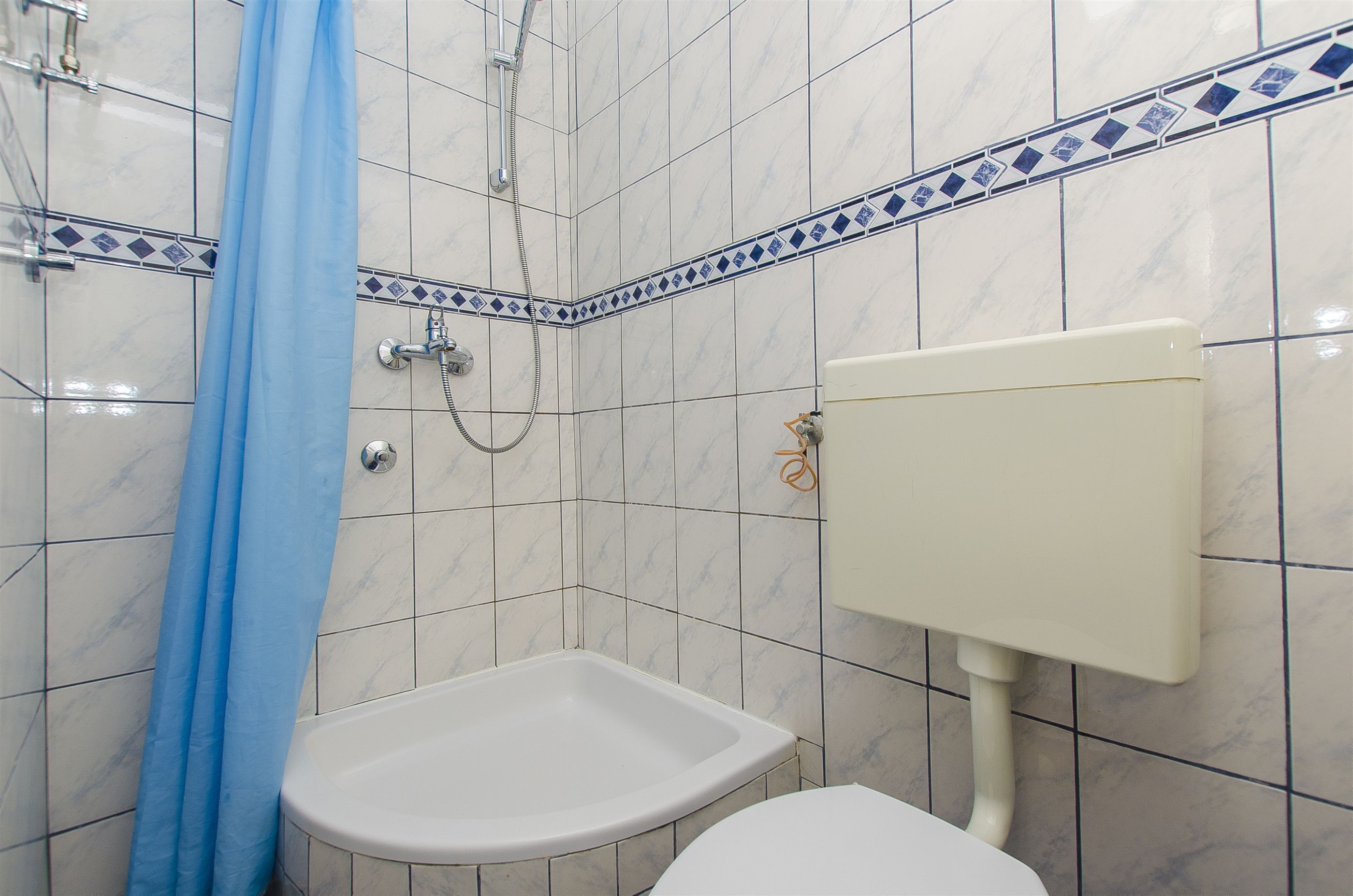 A bathroom with a white sink, a toilet, and a shower with a blue shower curtain.