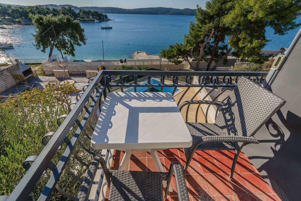 A terrace with a pool, outdoor seating, and a view of the sea.