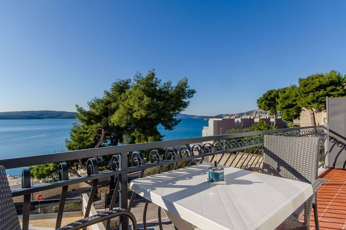 A terrace with a table and chairs overlooking a coastal view.