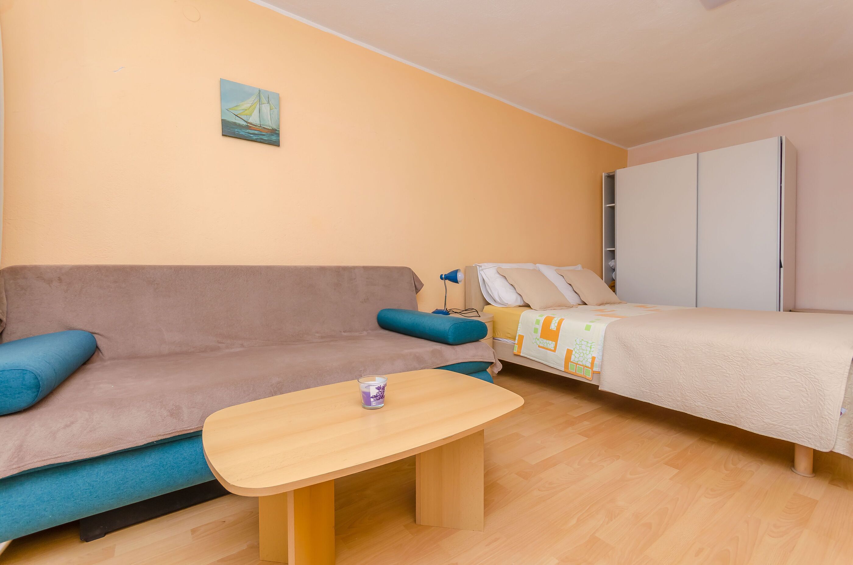 A cozy room with a sofa, a small table, a bed, and a wardrobe.