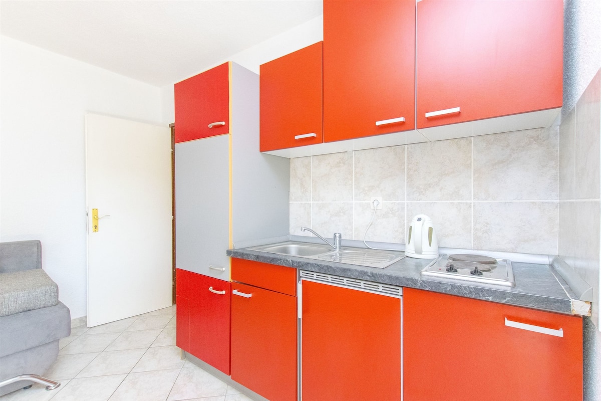 Una cucina con mobili rossi, un lavello e un piano cottura.