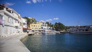 Une promenade en bord de mer bordée de bâtiments, un ciel dégagé et plusieurs bateaux amarrés.