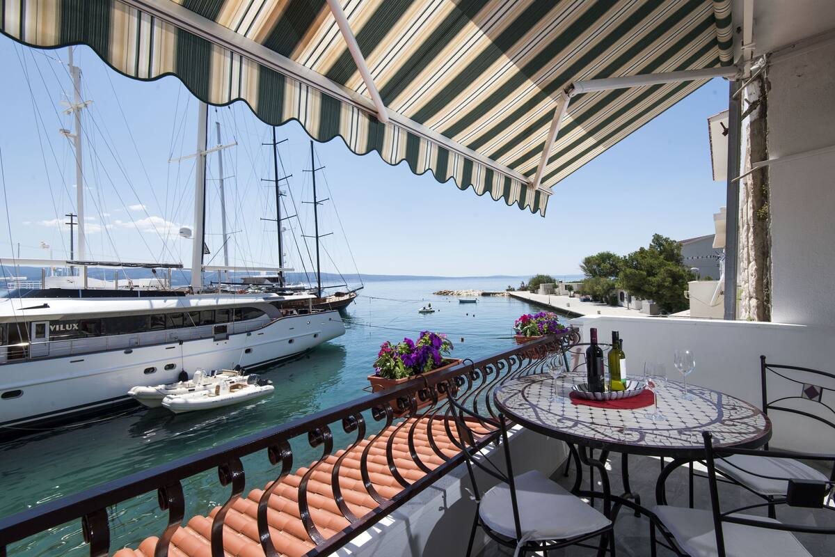 Ein Balkon mit Blick auf eine Marina, einem Esstisch mit Stühlen und einem Geländer.