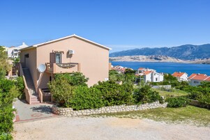 Un edificio beige con un'antenna parabolica, una scala e vista sul mare e sulle montagne.