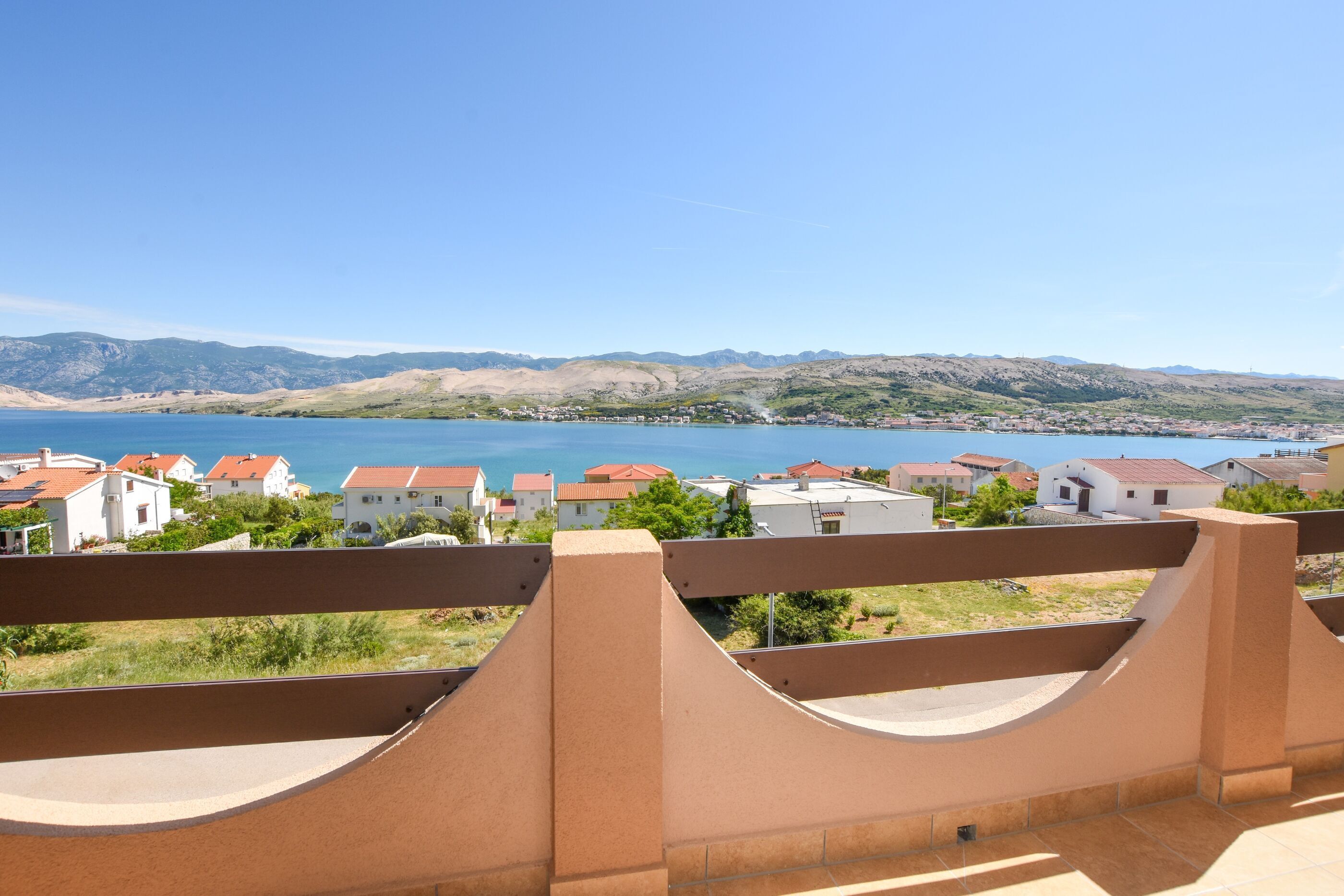 A coastal view with a balcony overlooking a beach and houses.