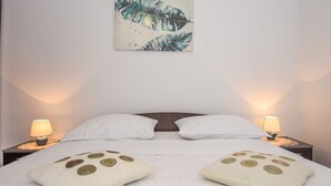 Ein ordentlich bezogenes Bett mit zwei Kissen, zwei Nachttischlampen und einem Wandbild.