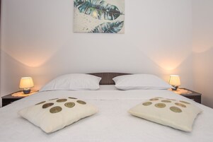 Un letto rifatto con due cuscini, due lampade da comodino e un quadro appeso al muro.