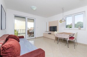 Un appartement moderne doté d’un canapé, d’une table à manger, d’une télévision et d’un balcon offrant une vue agréable.