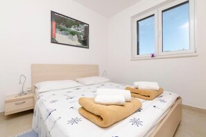 Une chambre à coucher avec un lit, deux oreillers, une table de chevet, un tableau encadré et une fenêtre.