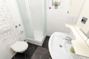 Une salle de bain avec des toilettes, une douche et un lavabo.