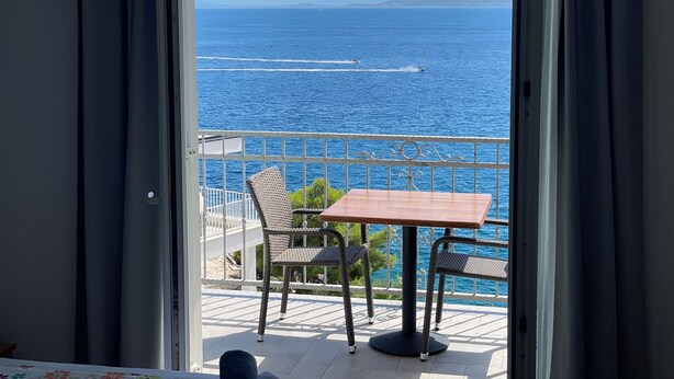 A balcony with a table and chairs overlooking a body of water with boats. - Apartments Jure (Okrug Gornji)