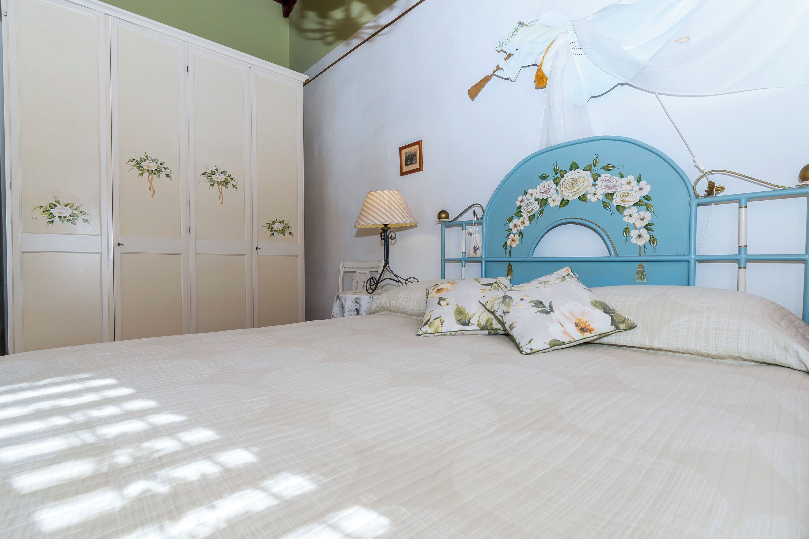 A bedroom with a bed, a nightstand, a lamp, and a wardrobe.
