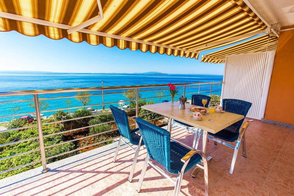 Un balcon avec une table et des chaises, offrant une vue sur la côte.