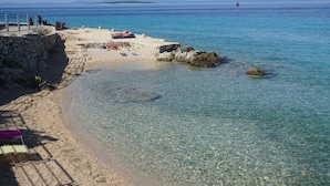 A clear beach with a stone wall and a pier extending into the water. - Apartments Ivan Sea View Lun (Lun)