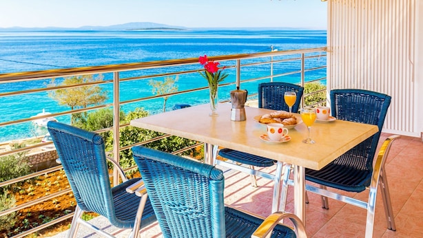 A balcony with a table set for breakfast, overlooking a coastal view. - Apartments Ivan Sea View Lun (Lun)