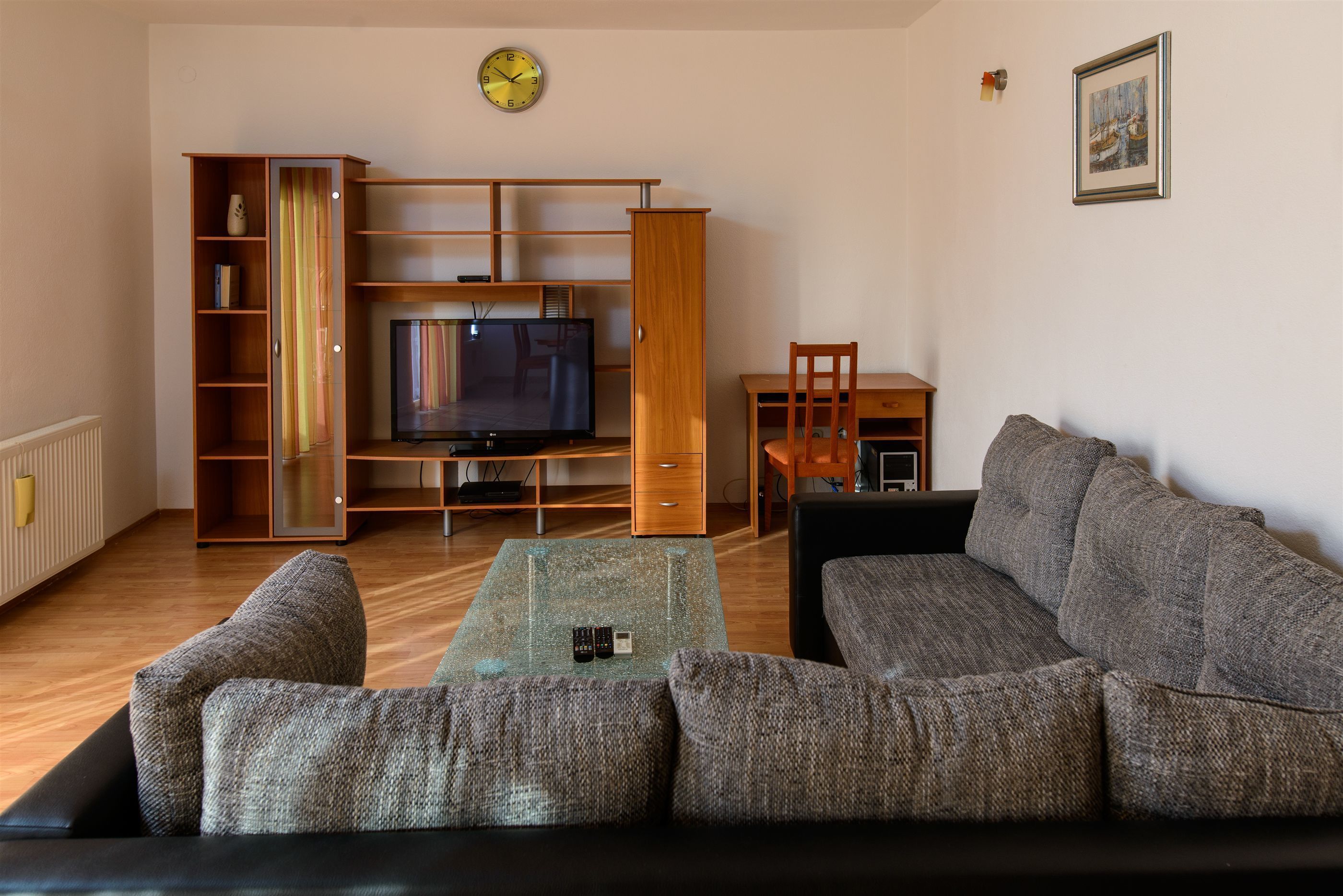 Ein Wohnzimmer mit einer Couch, einem Fernseher, einer Holz-Unterhaltungseinheit und einem kleinen Tisch.