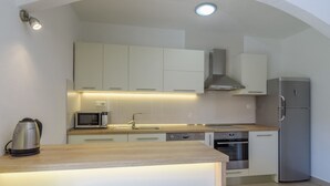 Une cuisine moderne avec des armoires blanches, des appareils en acier inoxydable et un plan de travail en bois.