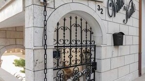 Una entrada de edificio con una reja de hierro forjado, un arco de piedra y una escalera que conduce a la entrada.