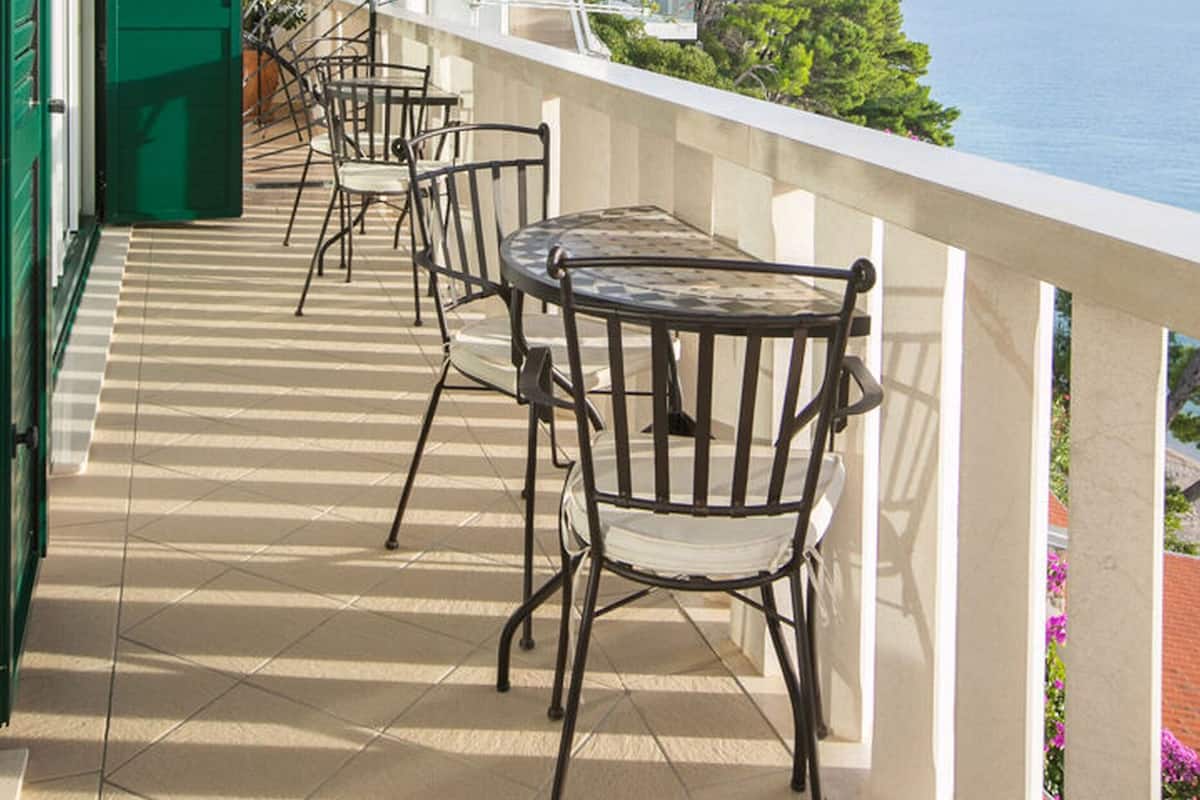 A balcony with a table and chairs, overlooking a body of water.
