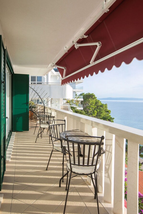 A balcony with a table and chairs, overlooking a body of water.