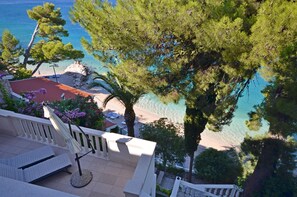 Ein Balkon mit Blick auf einen Strand und klares, blaues Wasser.