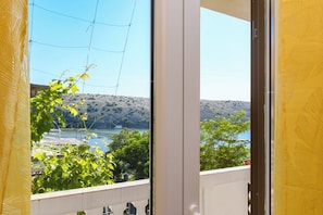 A balcony with a view of a lake, trees, and a hilly landscape.