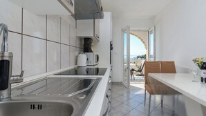 A modern kitchen with a stainless steel sink, a coffee machine, and a view to the outside. - Apartments Albina (Lopar)
