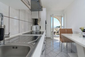 A modern kitchen with a stainless steel sink, a coffee machine, and a view to the outside. - Apartments Albina (Lopar)