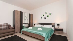 A modern bedroom with a bed, a wardrobe, a nightstand, and a sofa. - Apartment Danica (Sukosan)