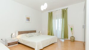 Une chambre à coucher avec un lit, des tables de chevet, une lampe, un vase avec une plante et un tableau au mur.