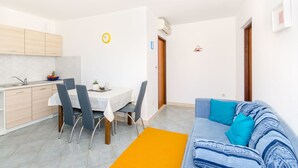 Une cuisine moderne avec un coin repas, un canapé avec des coussins bleus et une petite table avec des chaises.