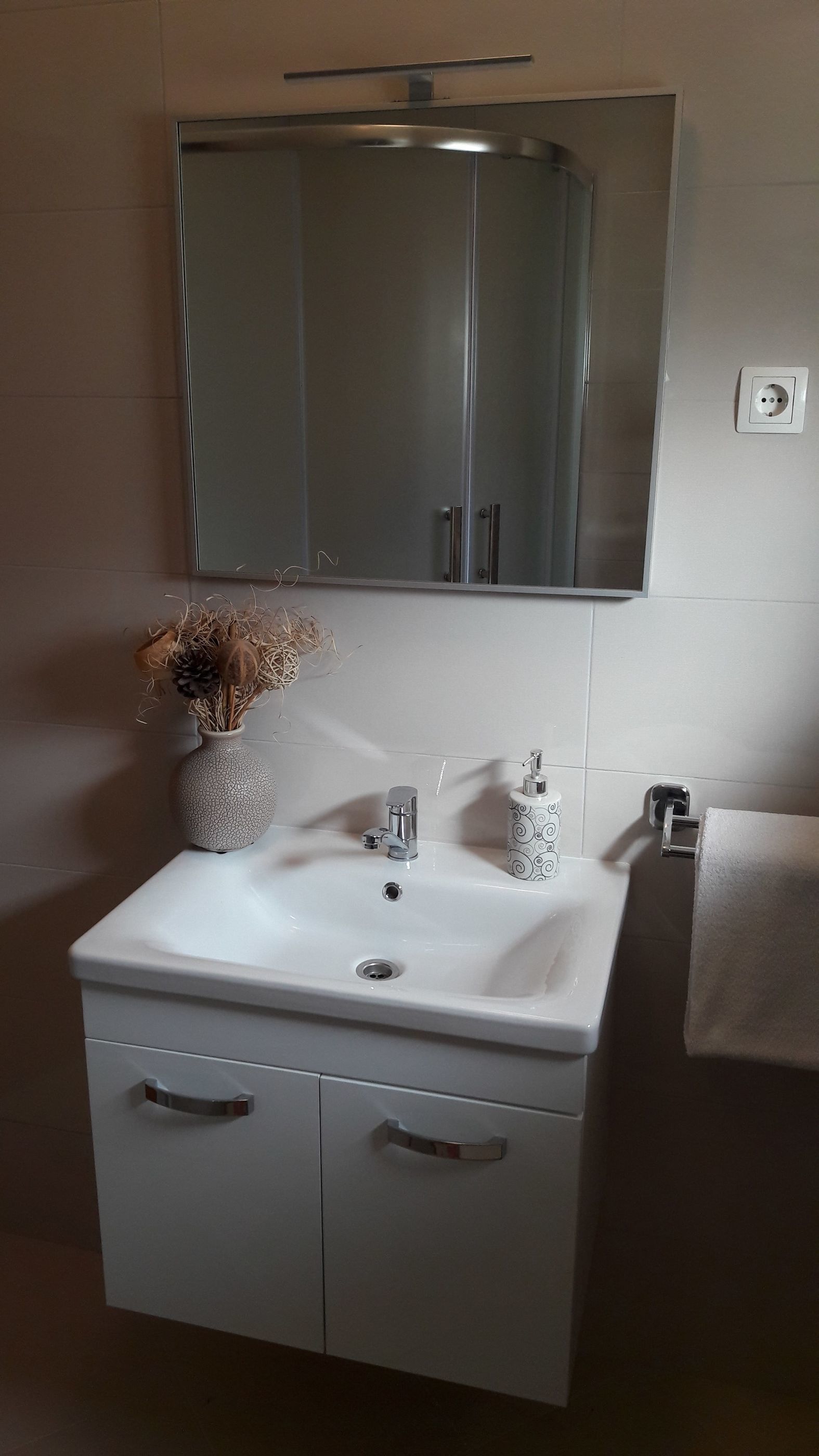 A bathroom with a white sink, a mirror above it, and a towel hanging on the wall.