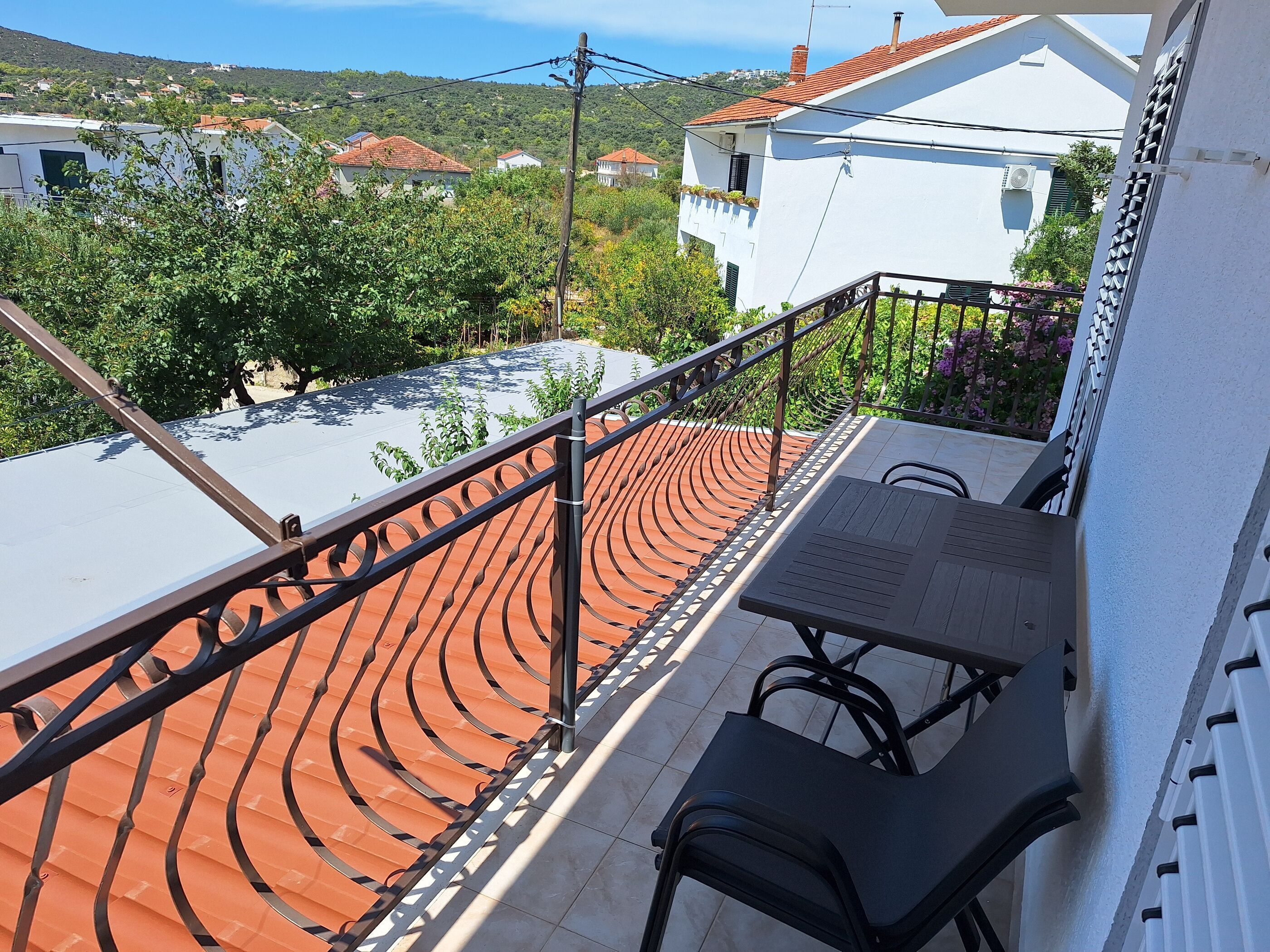 Un balcone con tetto in tegole, un tavolo e due sedie.