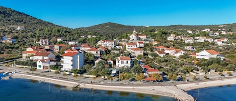 A coastal town with buildings, a church, and clear blue waters.