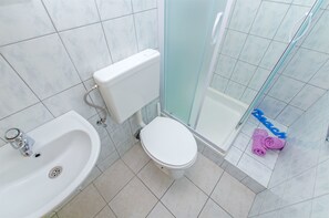 A bathroom with a sink, toilet, and glass shower enclosure. - Apartments Zecic (Omis)