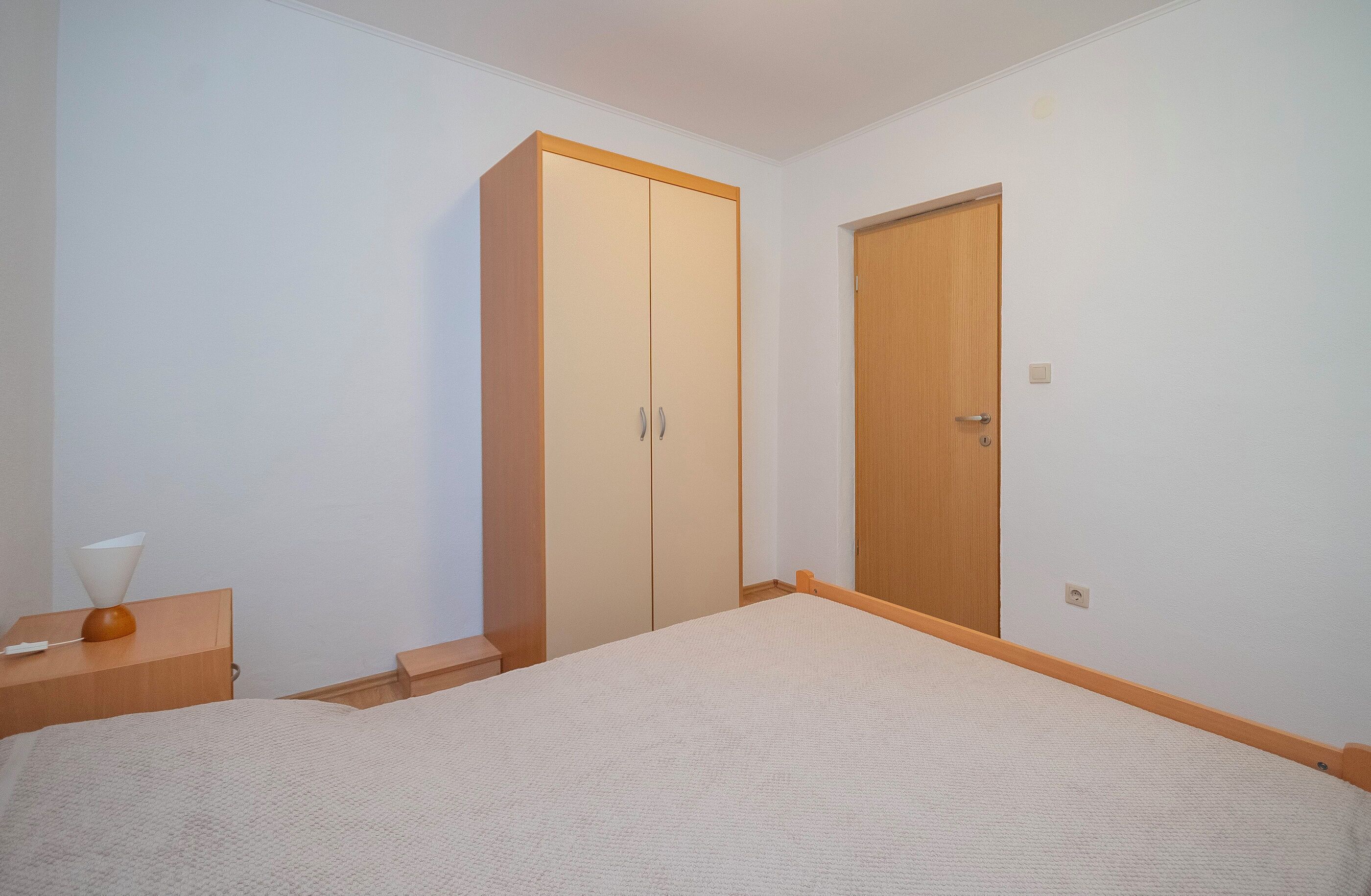 Un dormitori amb llit, armari i porta.